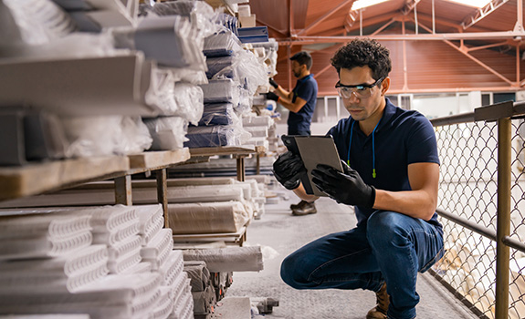 man working at a manufacturing factory and making an inventory of the merchandise using a digital tablet